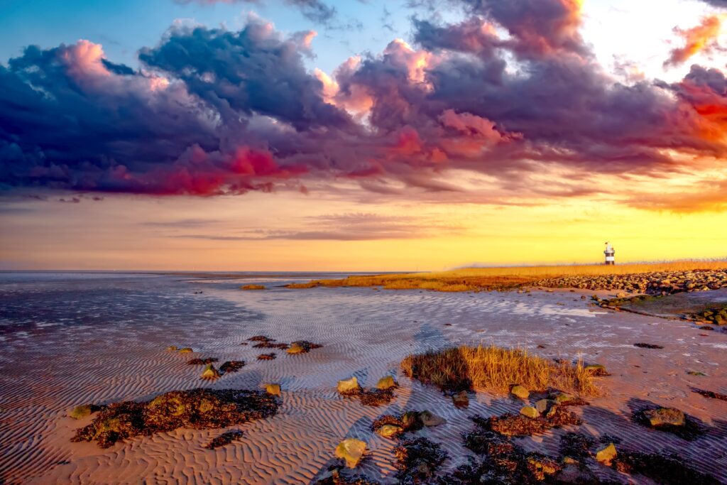 Dramatischer Sonnenuntergang über dem Watt mit dunklen Wolken und Prielen – Wetter Wurster Nordseeküste.